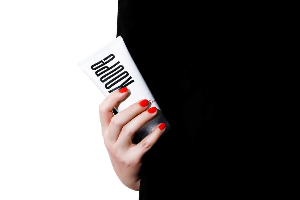 A hand with red nails holds a koope product
