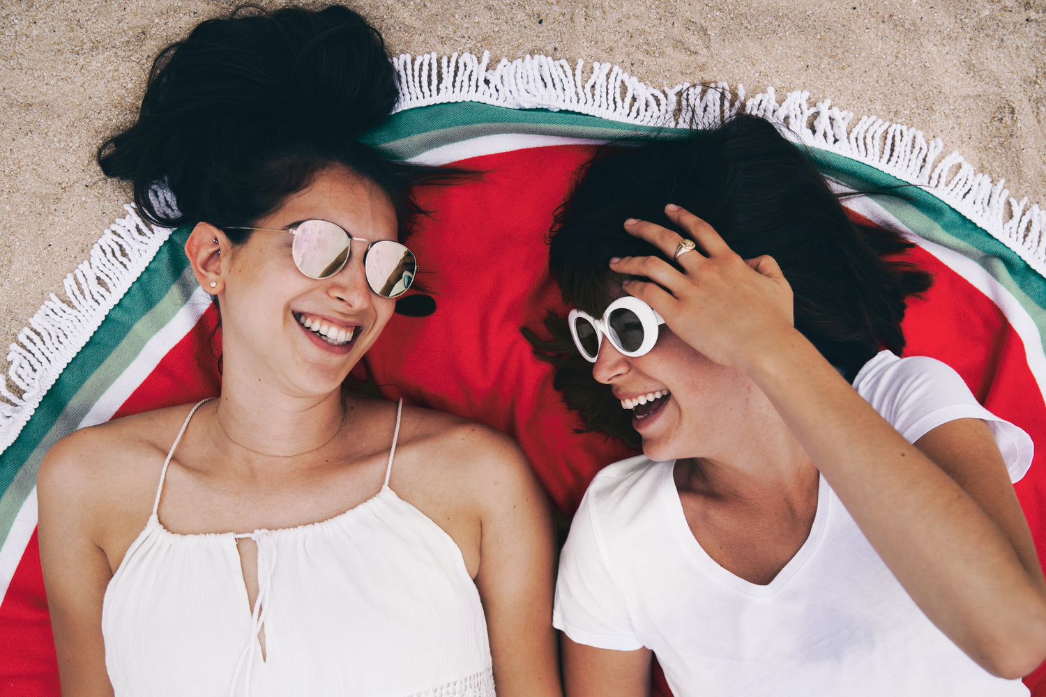 Two women are lying on a red blanket